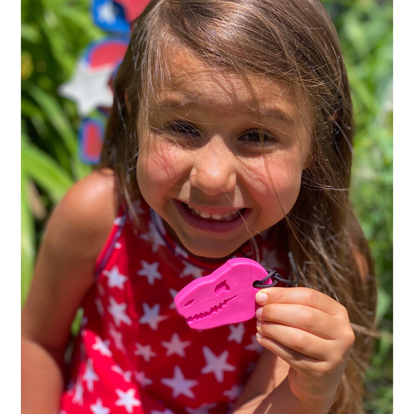 Girl holding Ark Dino-Bite Chewable necklace